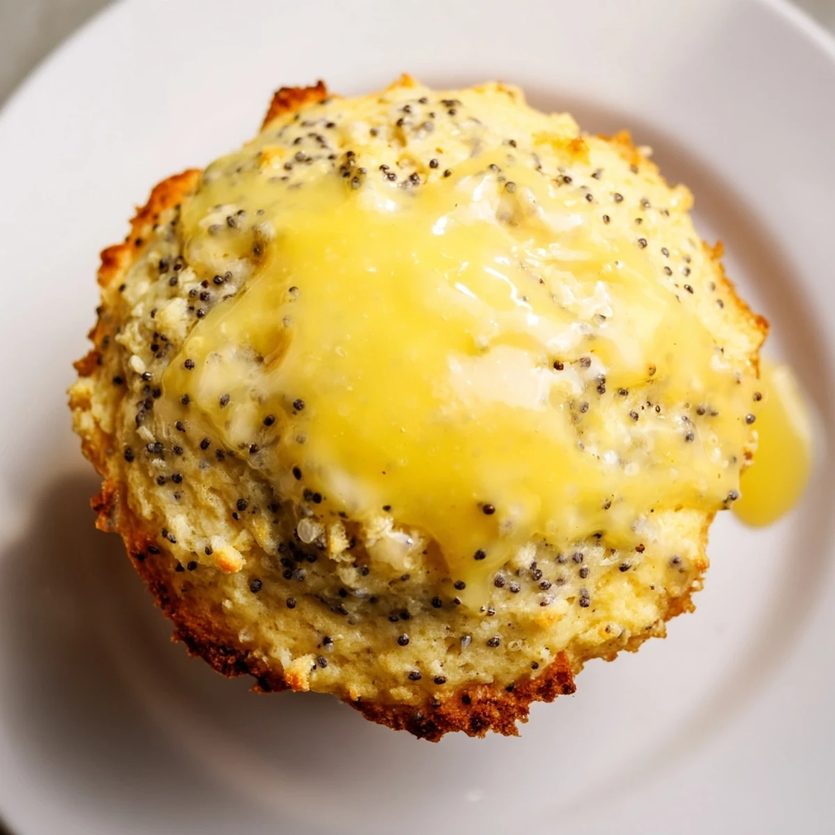 Freshly baked Lemon Poppy Seed Muffins resting on a wire rack with a glossy lemon glaze dripping down the sides.