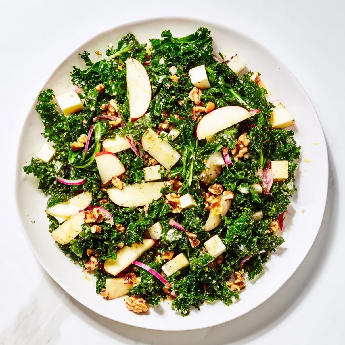A vibrant bowl of Winter Kale Salad with Apple and Cheddar featuring sweet-tart apples, savory cheese, and crunchy pecans.