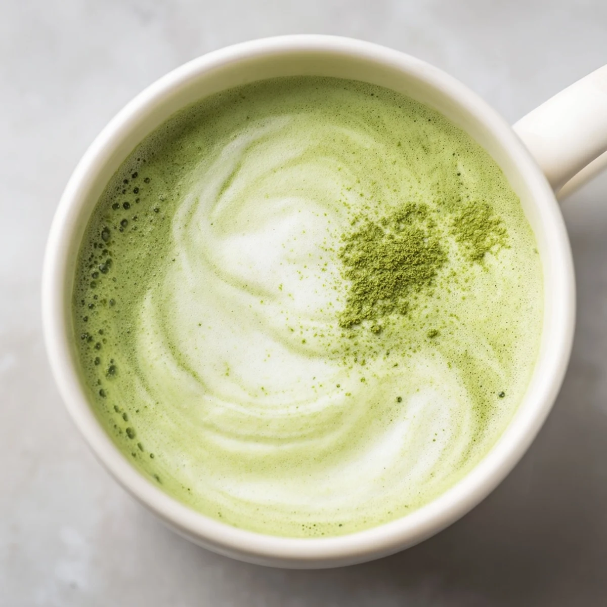 A creamy Green Matcha Latte with Almond Milk topped with soft foam, set on a cozy wooden table with morning light.