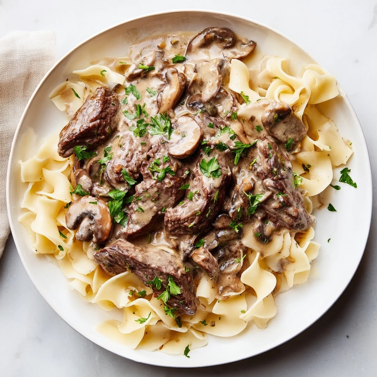 Comforting Beef Stroganoff with Egg Noodles on a dinner plate, rich sauce coating every strand warmly.