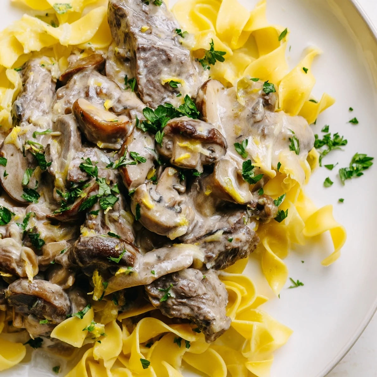 This comforting Beef Stroganoff is served over golden egg noodles and garnished with parsley.