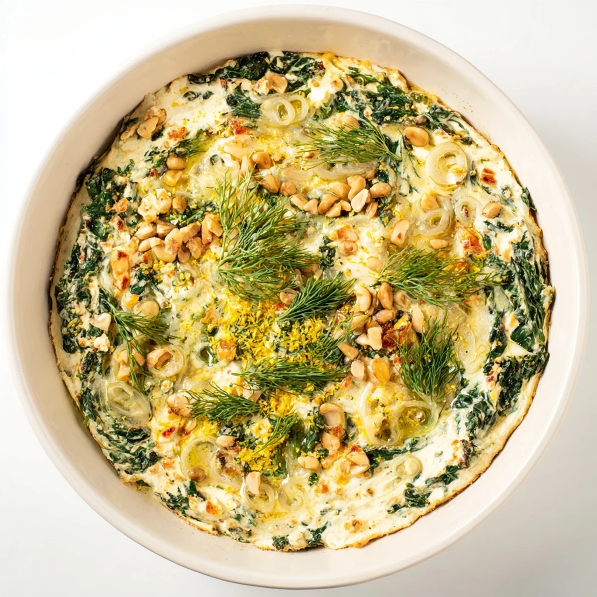 Spinach and Pepperoncini Baked Feta Dip served warm in a baking dish, garnished with lemon zest and herbs, alongside sliced baguette for a delicious vegetarian appetizer spread.