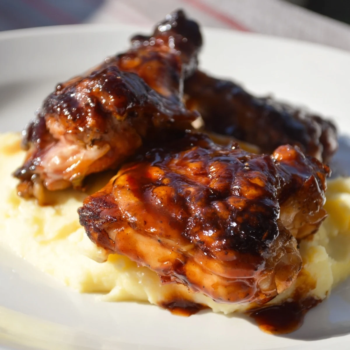 Golden-brown chipotle honey chicken thighs glisten beside creamy smoked Gouda mashed potatoes on a rustic wooden table.
