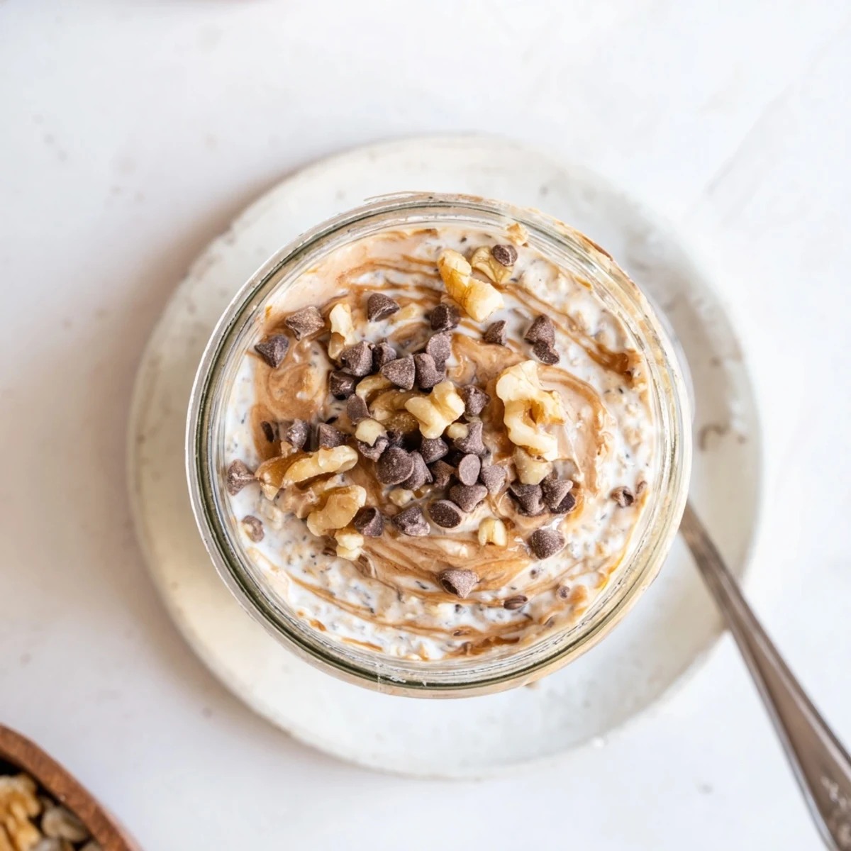 Cookie Dough Overnight Oats showcase a thick, rich texture swirled with almond butter and a dusting of cinnamon.