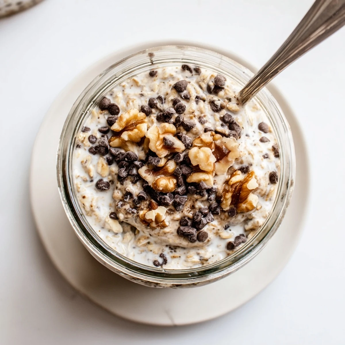 A wholesome breakfast bowl with rolled oats, Greek yogurt, and maple syrup, garnished with extra chocolate chips and pecans.