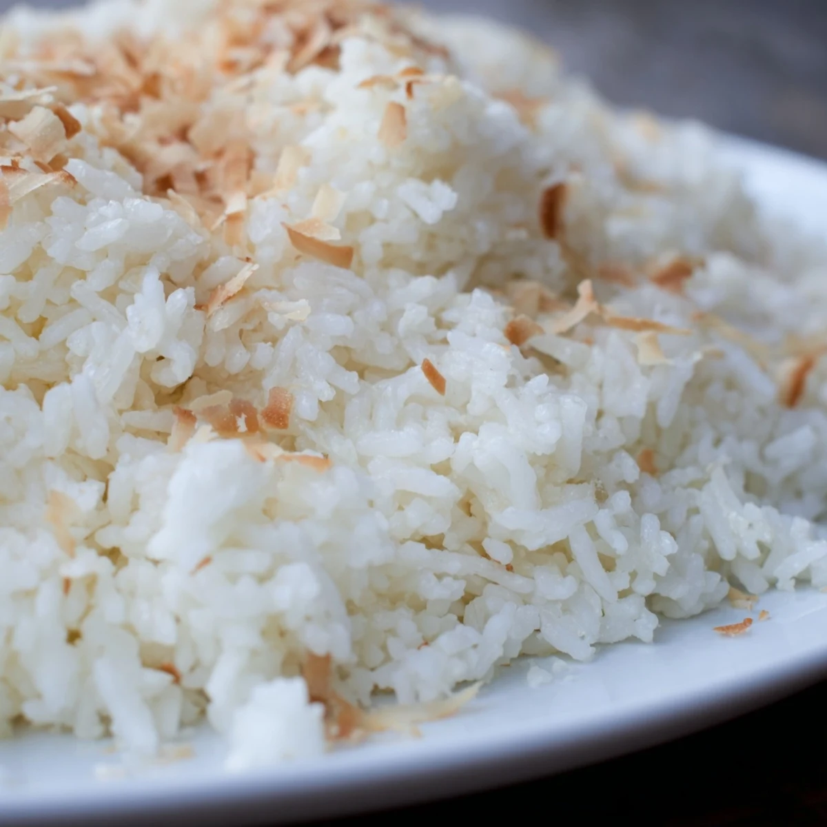 Fluffy The Best Coconut Rice steamed in coconut milk and water, garnished with toasted flakes, served alongside grilled chicken.