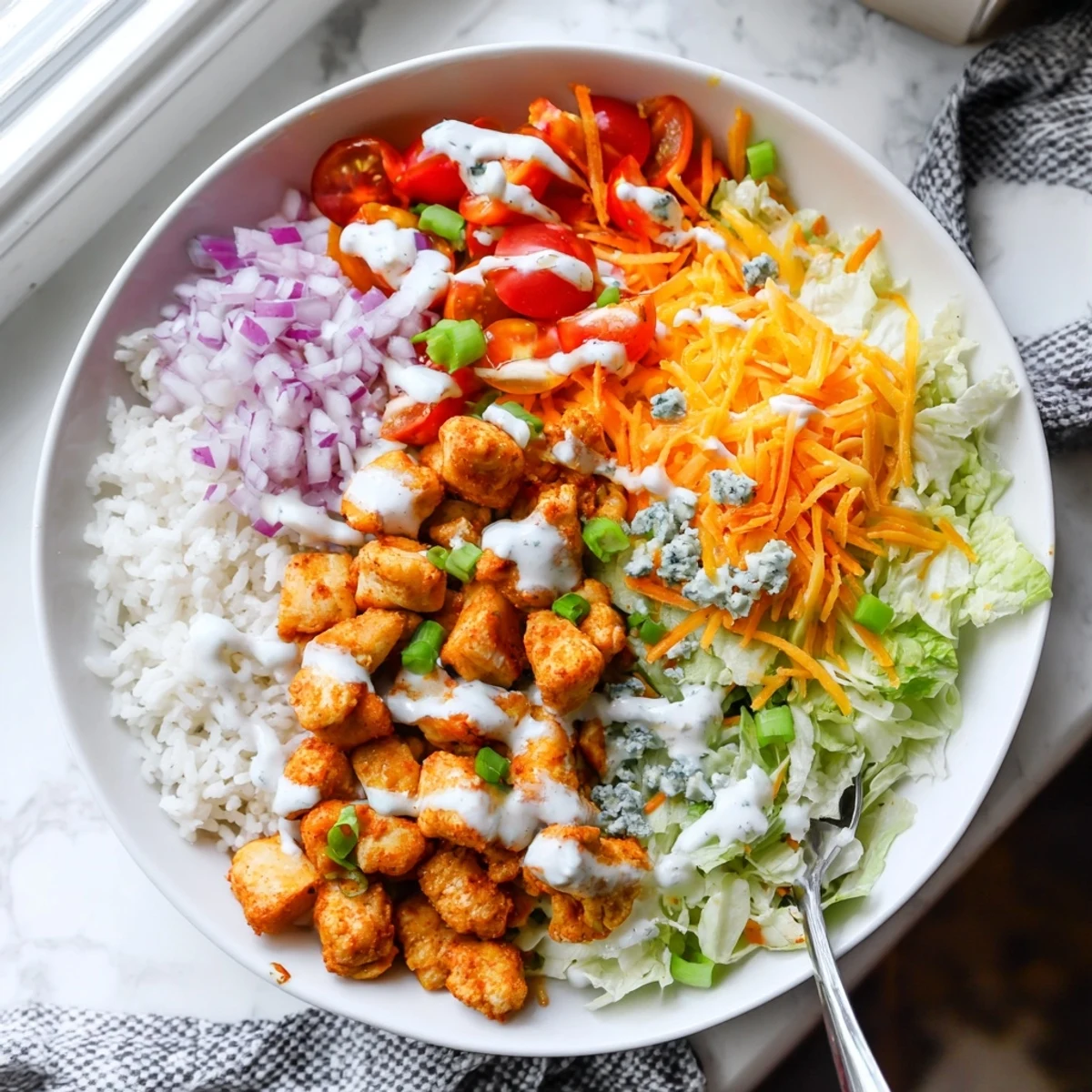 Close-up photo of Buffalo Chicken Bowls with spicy chicken, fluffy rice, and creamy ranch drizzled over crisp veggies.