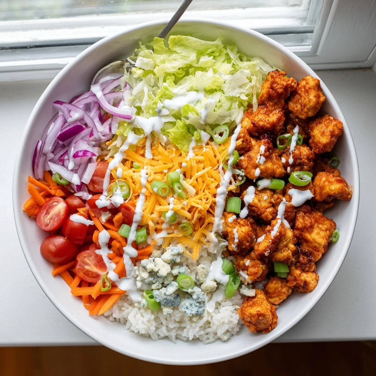 Buffalo Chicken Bowls served with shredded cheddar, blue cheese crumbles, and a side of crunchy celery sticks.