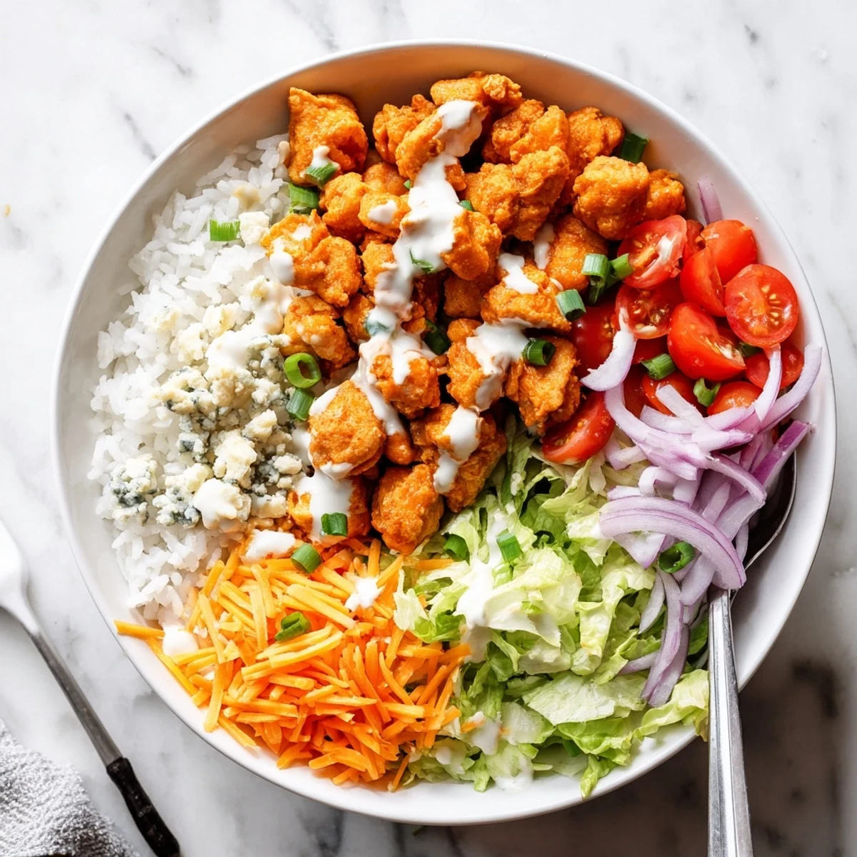 Colorful Buffalo Chicken Bowls topped with fresh romaine, tomatoes, and green onions on a rustic wooden table.