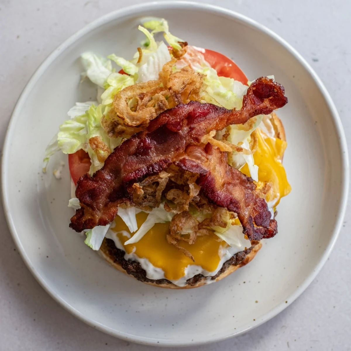 Close-up of Crack Burgers topped with crunchy bacon, melted cheddar, shredded lettuce, and ripe tomato slices.