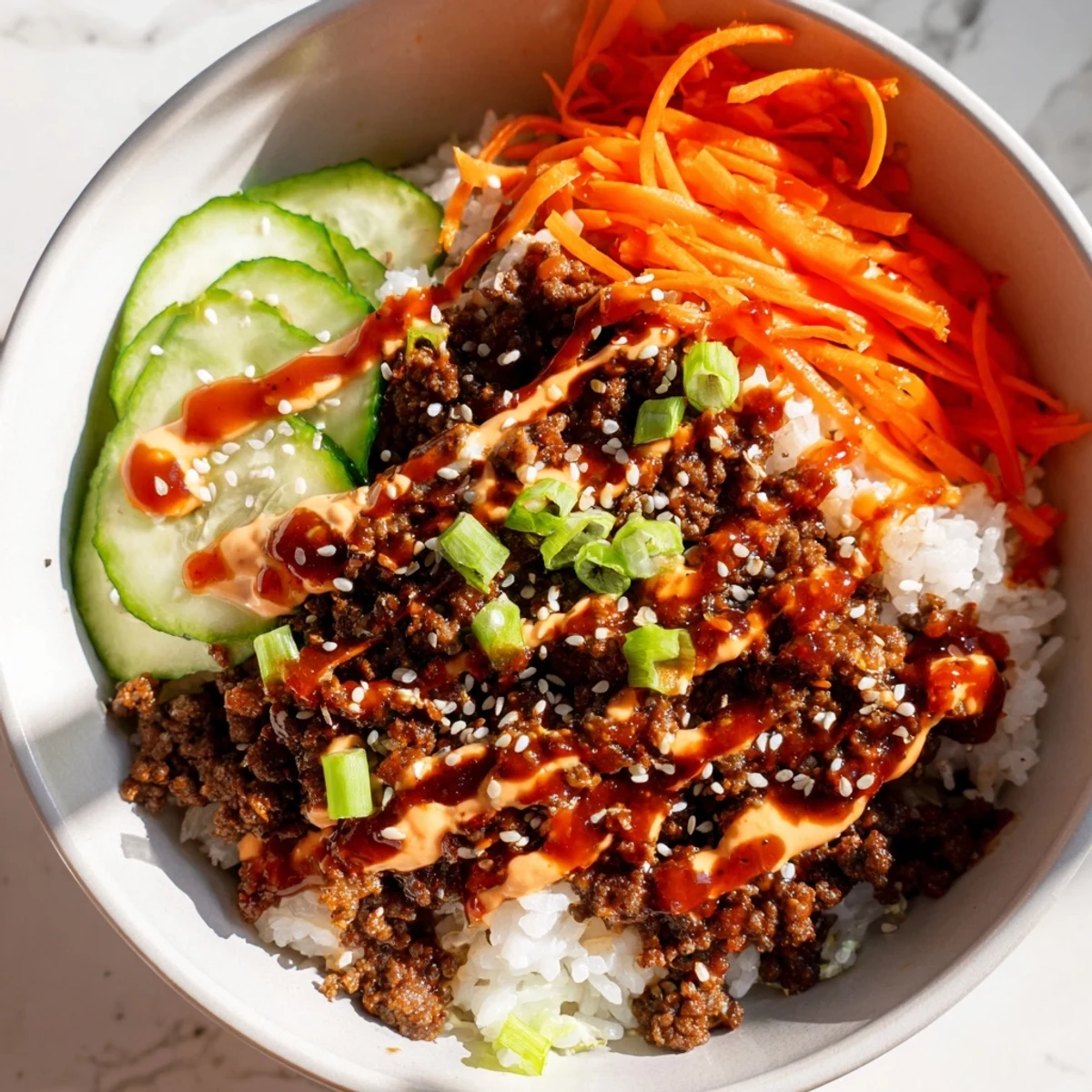 A close-up of Korean Beef Bowl with Spicy Mayo shows tender glazed beef, fluffy rice, and colorful veggies on a white plate, ready to eat.