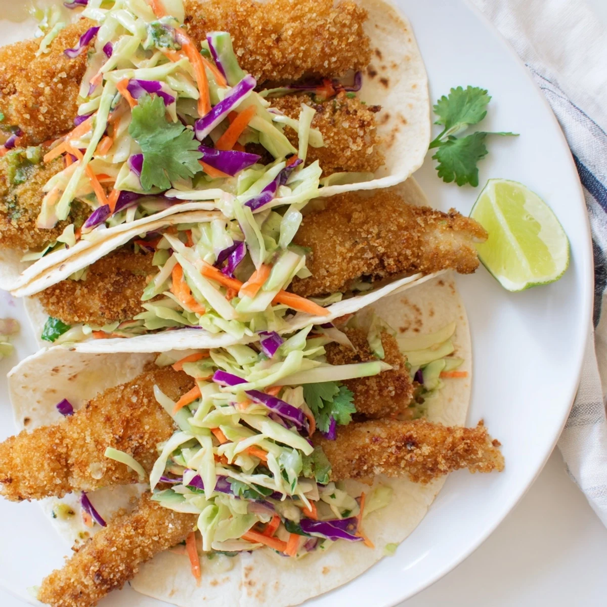 Crispy fish tacos piled high with crunchy cilantro lime coleslaw and fresh shredded carrots