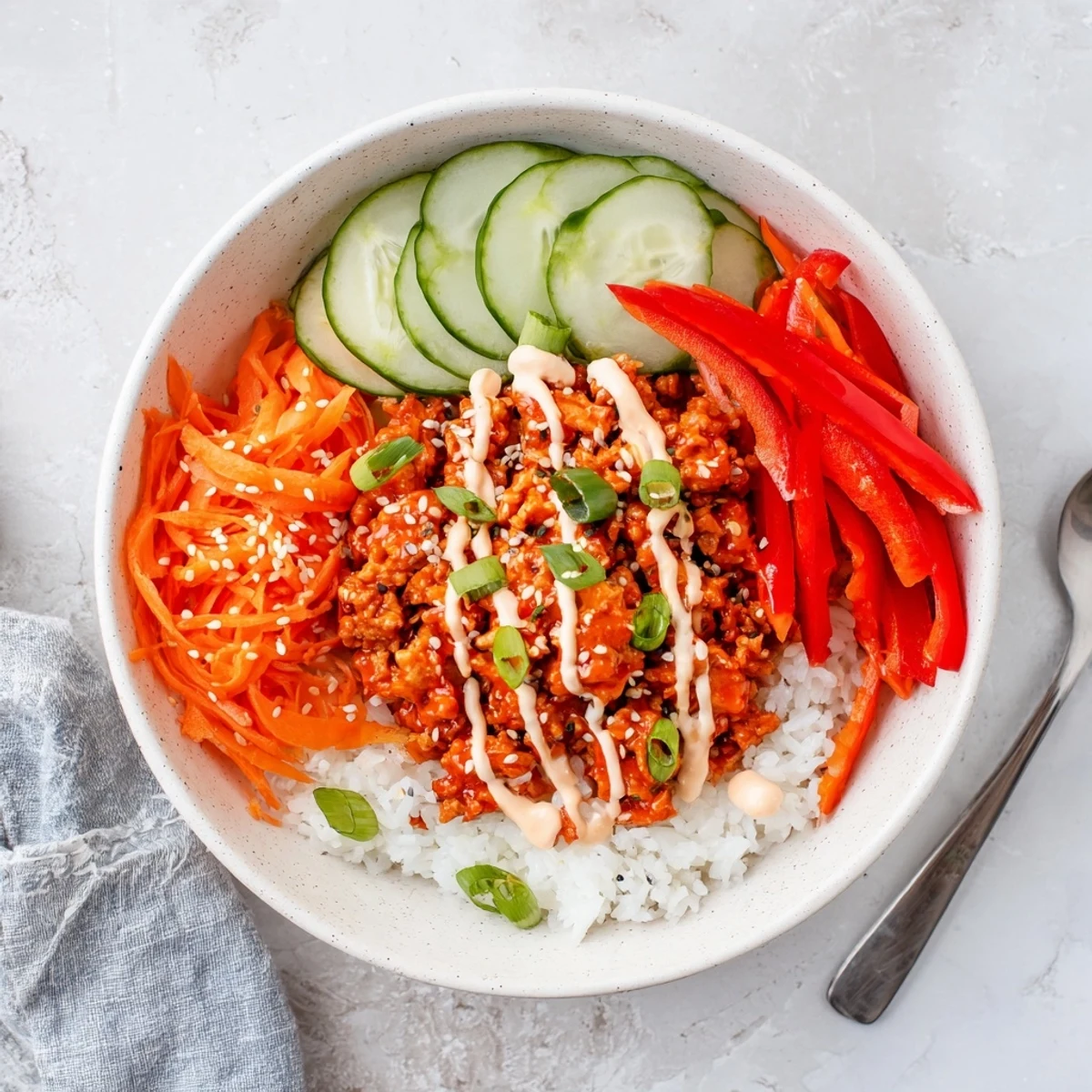 Asian-inspired firecracker ground chicken bowl with fiery sauce and fresh cucumber carrot toppings