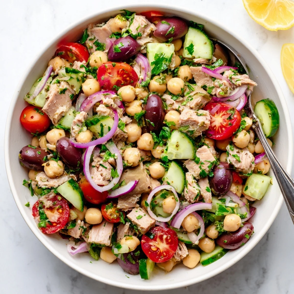 Hearty tuna and garbanzo bean salad featuring cherry tomatoes cucumber olives and fresh herbs