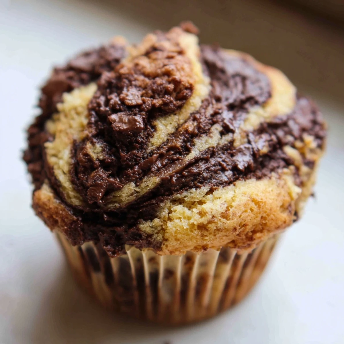Golden Nutella banana swirl muffins baked to perfection with rich chocolate ribbons