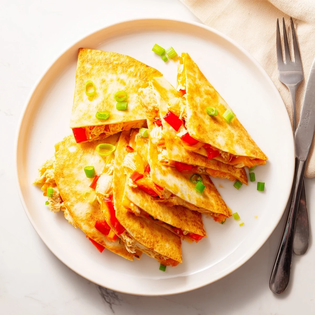 Four easy baked chicken and cheese quesadillas arranged on a baking sheet with golden tortilla edges