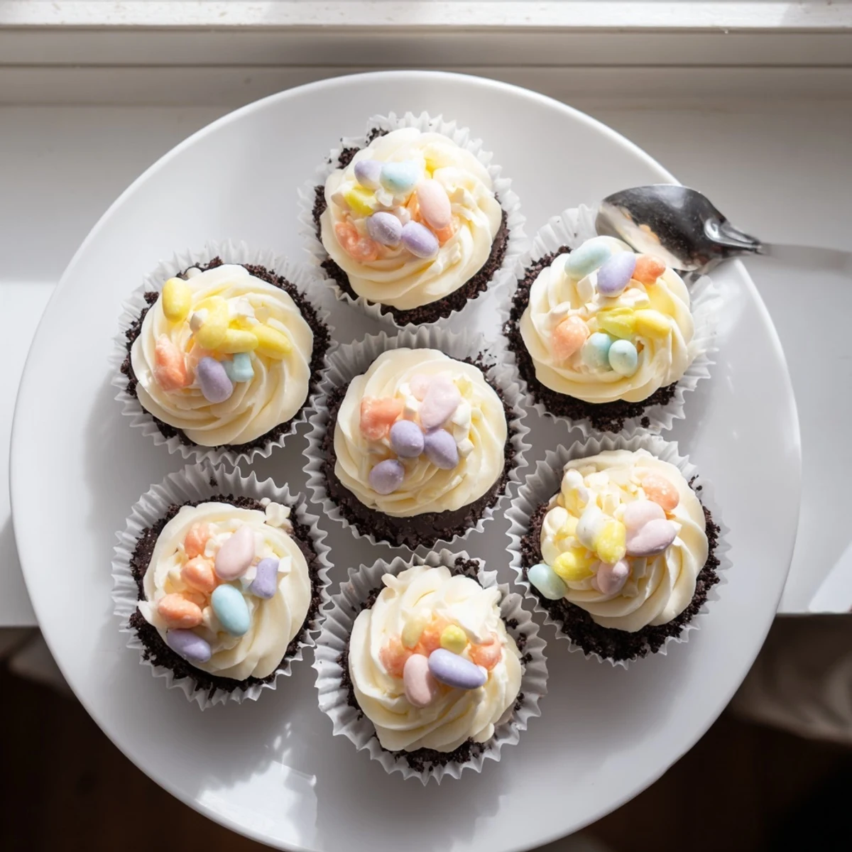 Easter Cadbury Mini Cheesecakes topped with whipped cream and colorful candy eggs on a white plate