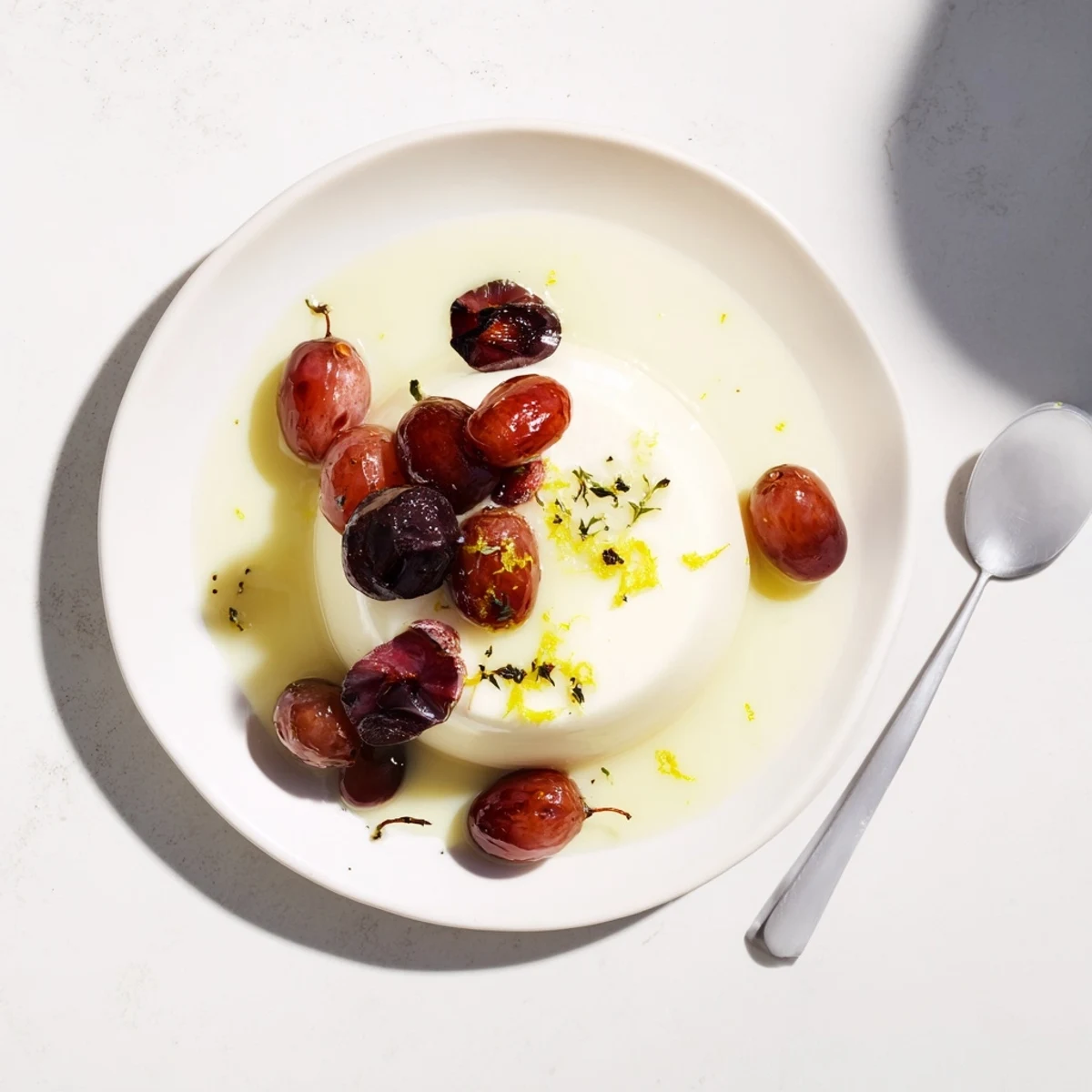 Individual lemon panna cotta servings drizzled with caramelized grape juices