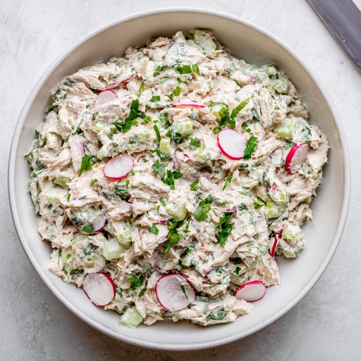 Creamy Green Goddess Chicken Salad Dip served in a white bowl with fresh herb garnish and crackers