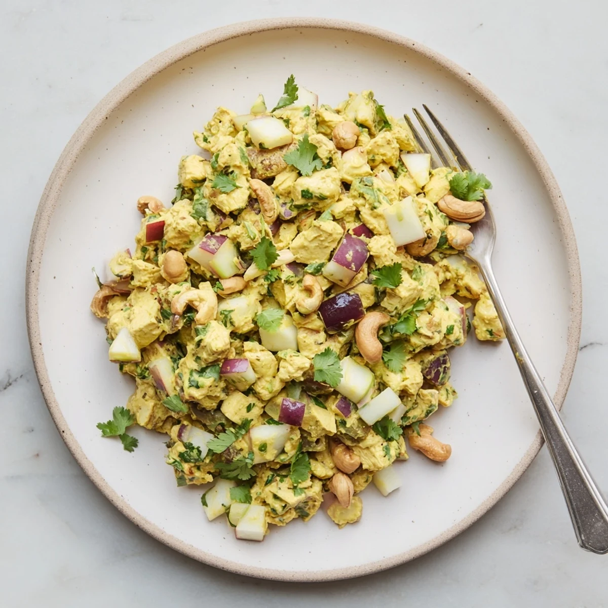 Golden curry chicken salad with tender chunks, crisp apples, grapes, and creamy spiced dressing in a white serving bowl