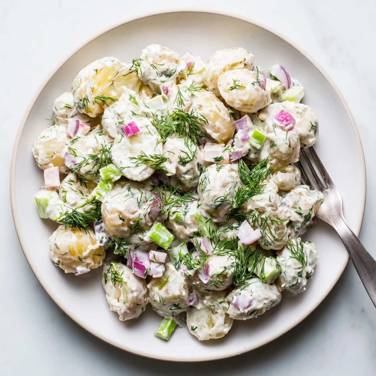 Light and tangy Greek yogurt potato salad topped with green herbs and crunchy diced vegetables