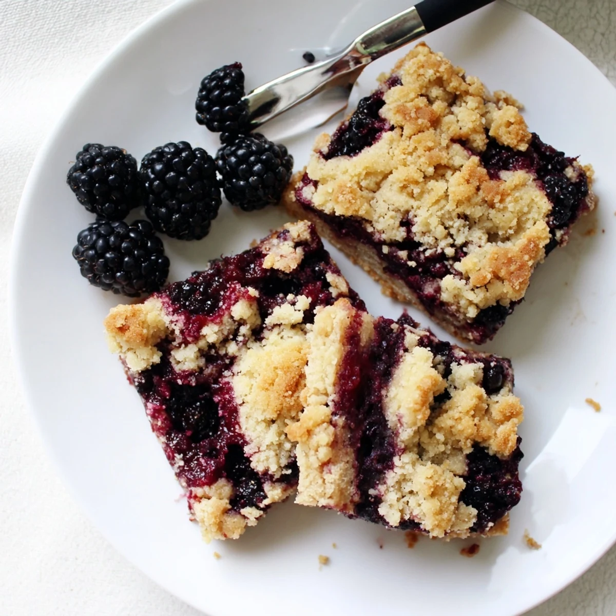 Perfect blackberry crumble bars sliced into squares showing layered fruit filling and golden brown crumble topping