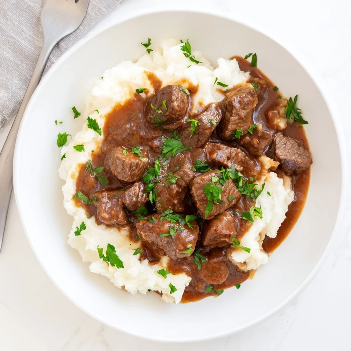 Fork-tender slow cooker beef tips and gravy plated with steamed white rice and chopped herbs