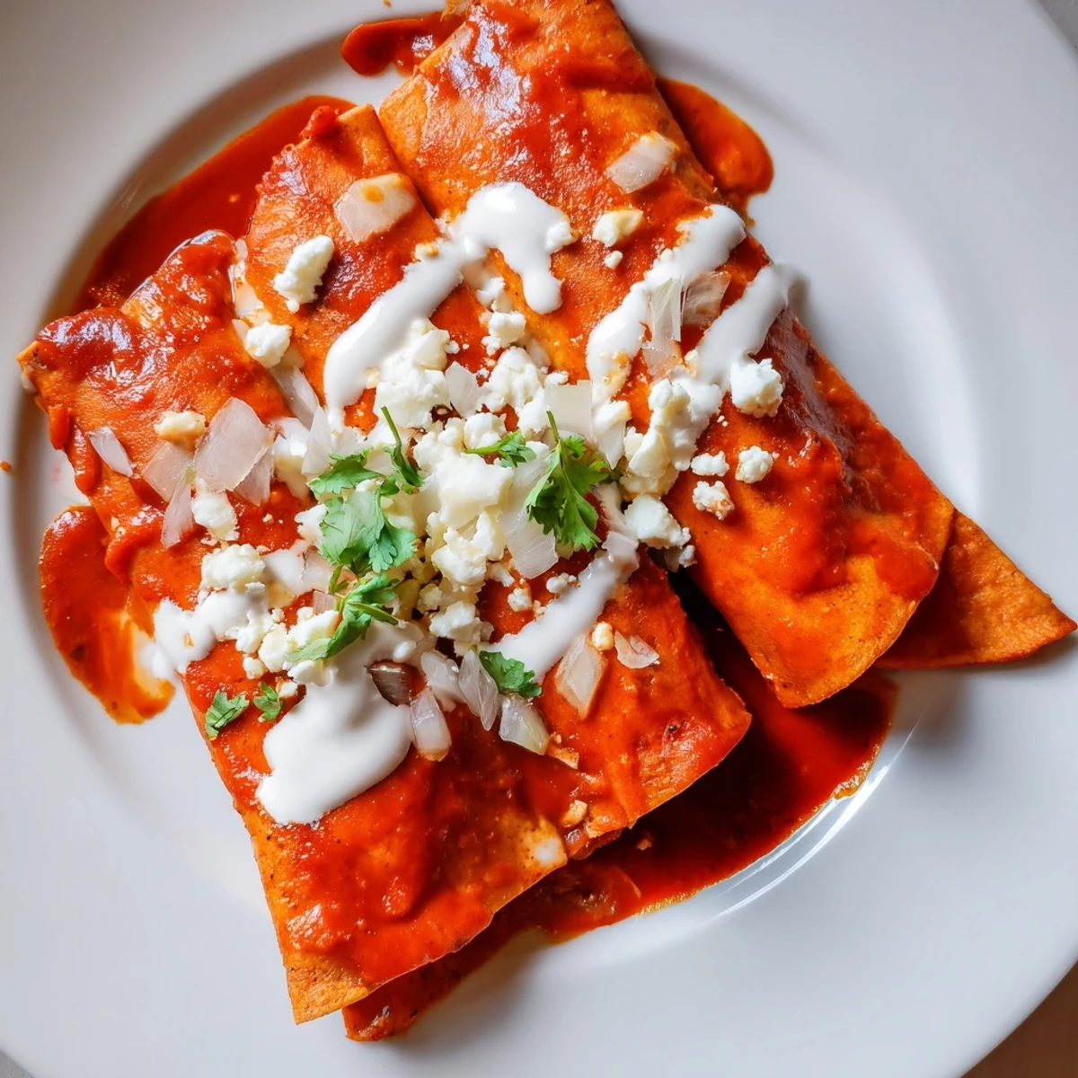 Golden entomatadas draped in rich tomato sauce topped with crumbled queso fresco and fresh cilantro
