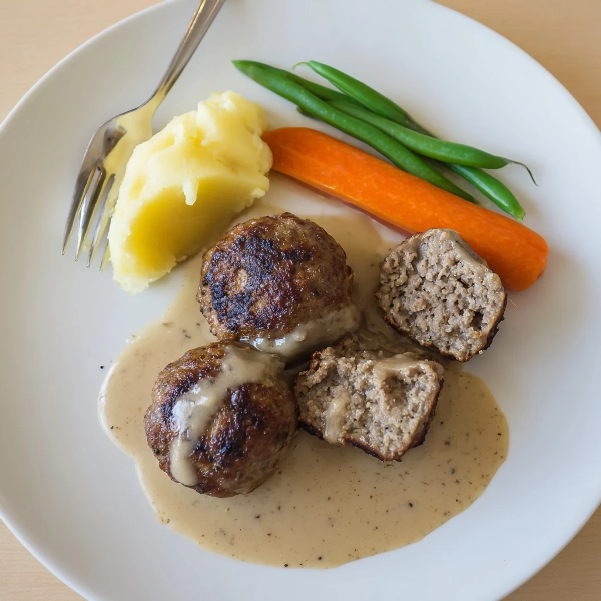 Pan-seared Homemade Ikea Meatballs bubbling gently in rich sauce, with lingonberry jam