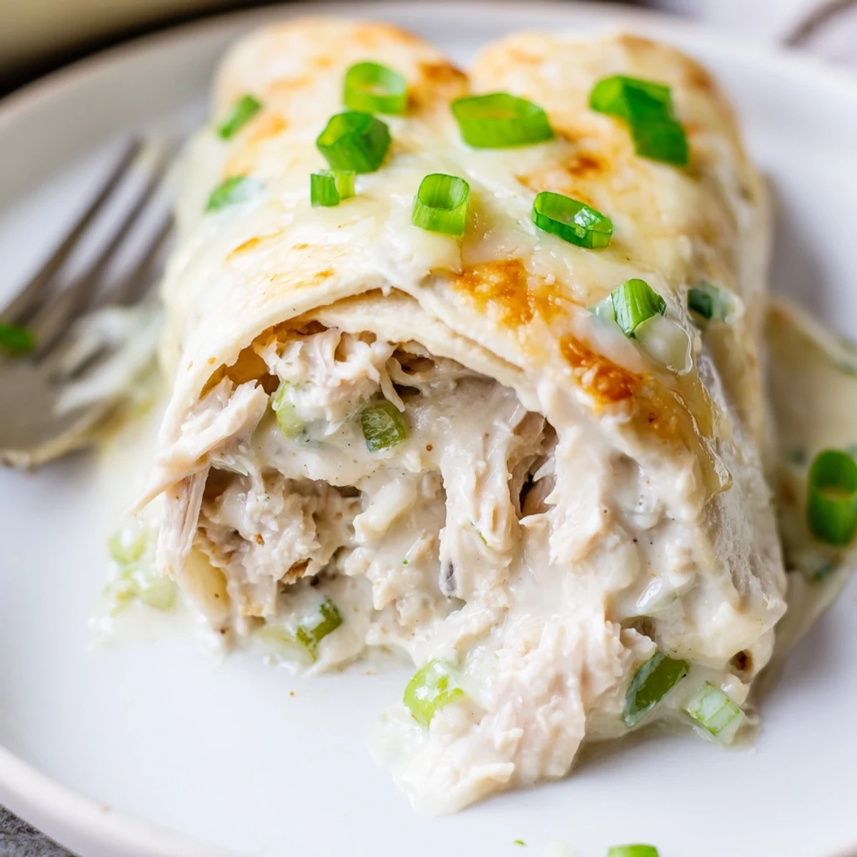 Sliced Creamy White Chicken Enchiladas revealing tender chicken and velvety white sauce