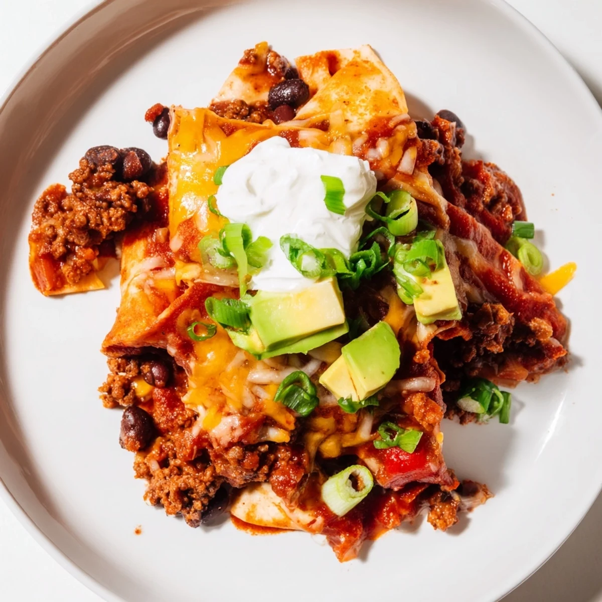 Hot Beef Skillet Enchiladas served with sour cream, avocado, scallion slices