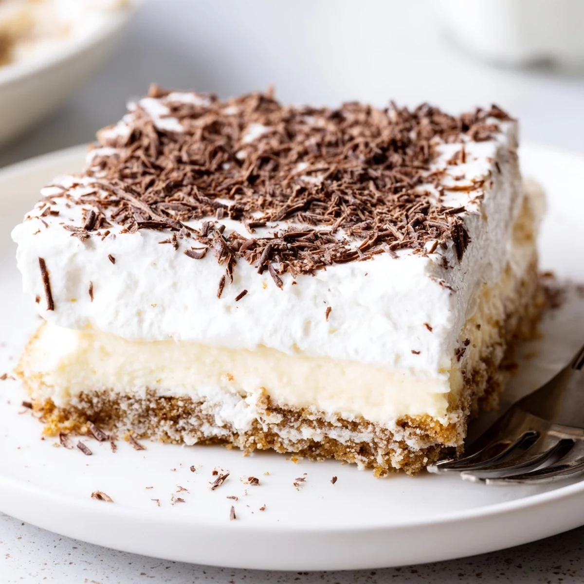 No Bake Layered Dessert chilled in a glass dish, creamy vanilla layers.