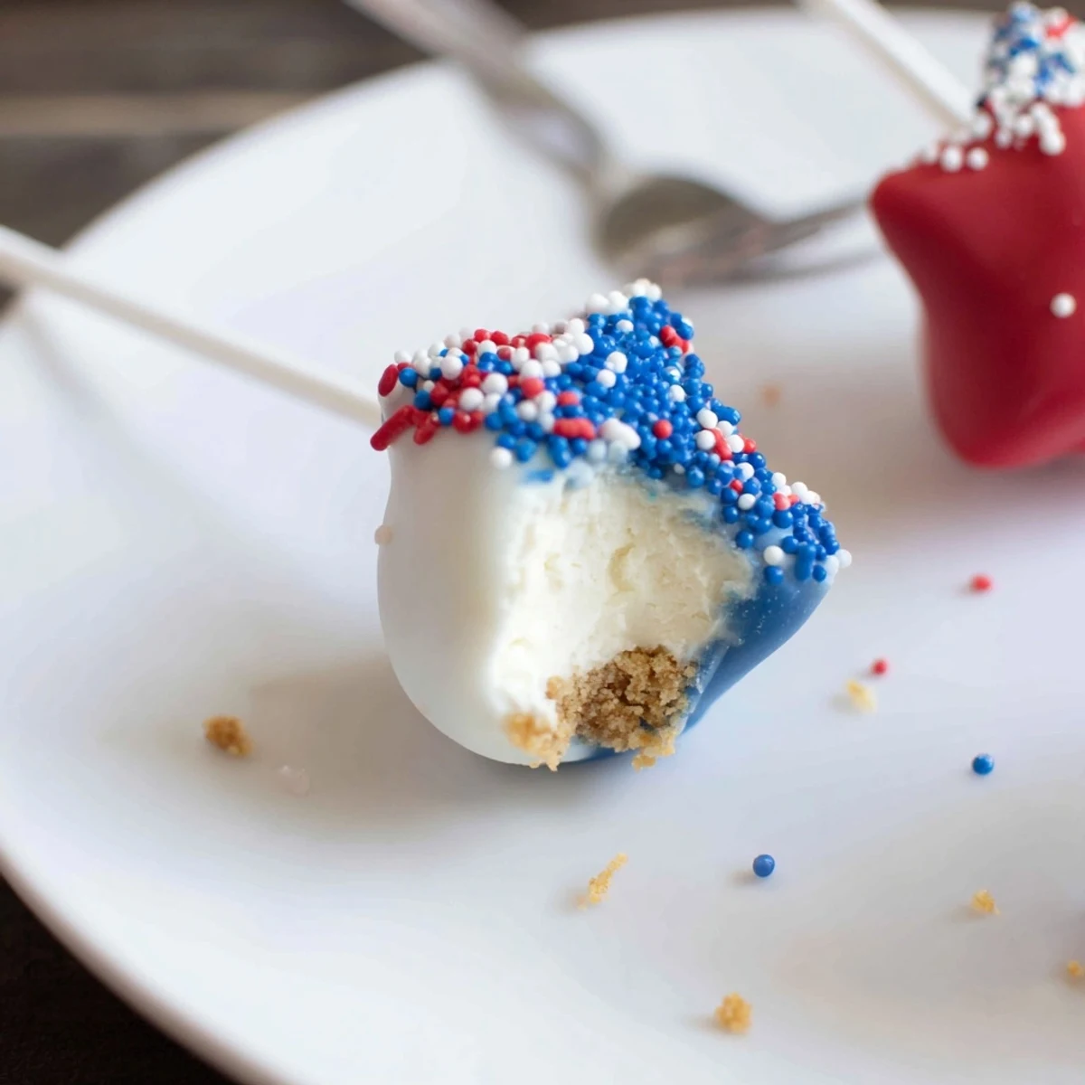 Fourth Of July Star Cheesecake Pops glistening with red, white, blue sprinkles, handheld