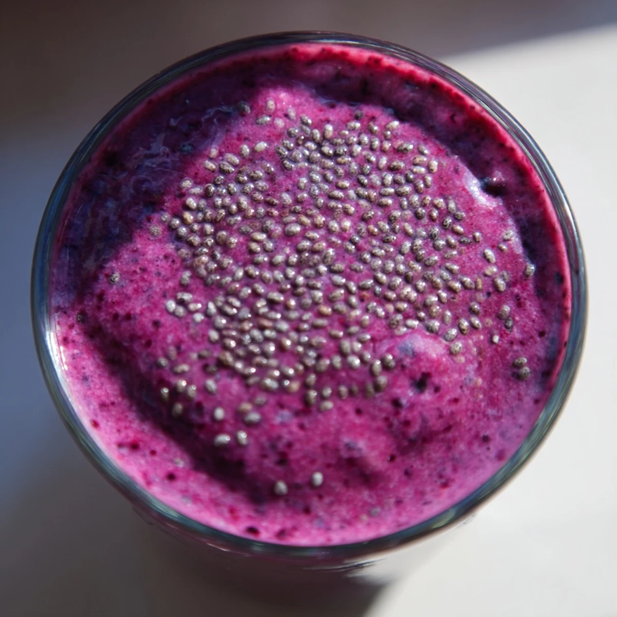 Vibrant chia seed smoothie poured into mason jars with floating black speckles