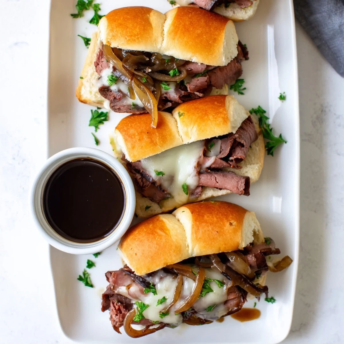 Golden French dip sliders oozing melted provolone over tender roast beef nestled in toasted brioche rolls with rich au jus for dipping
