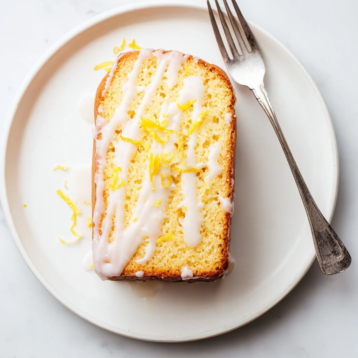 Freshly baked lemon yogurt loaf with golden crust and citrus glaze on white plate