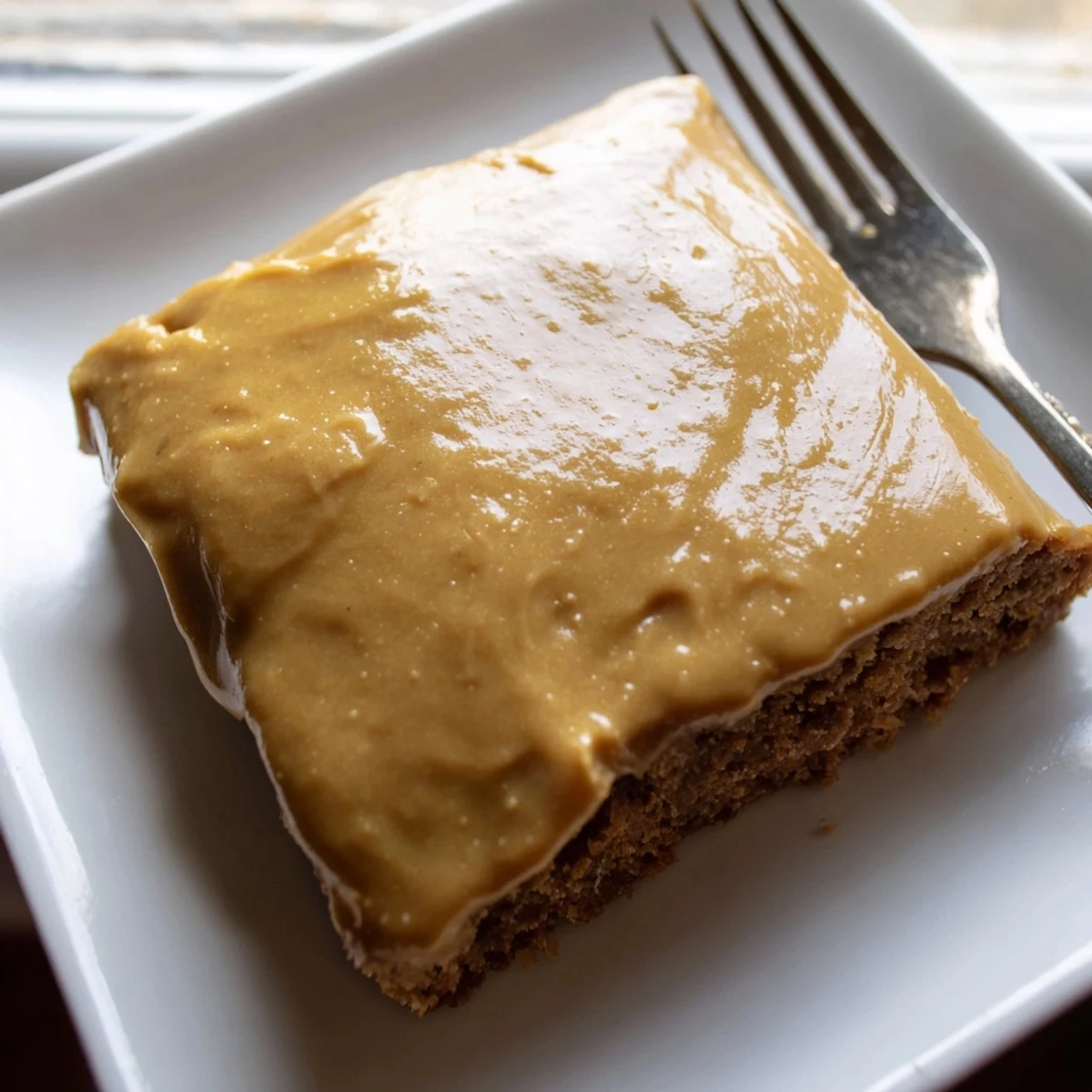 Square fudgy banana bread brownies drizzled with golden brown butter frosting and sprinkled with walnuts