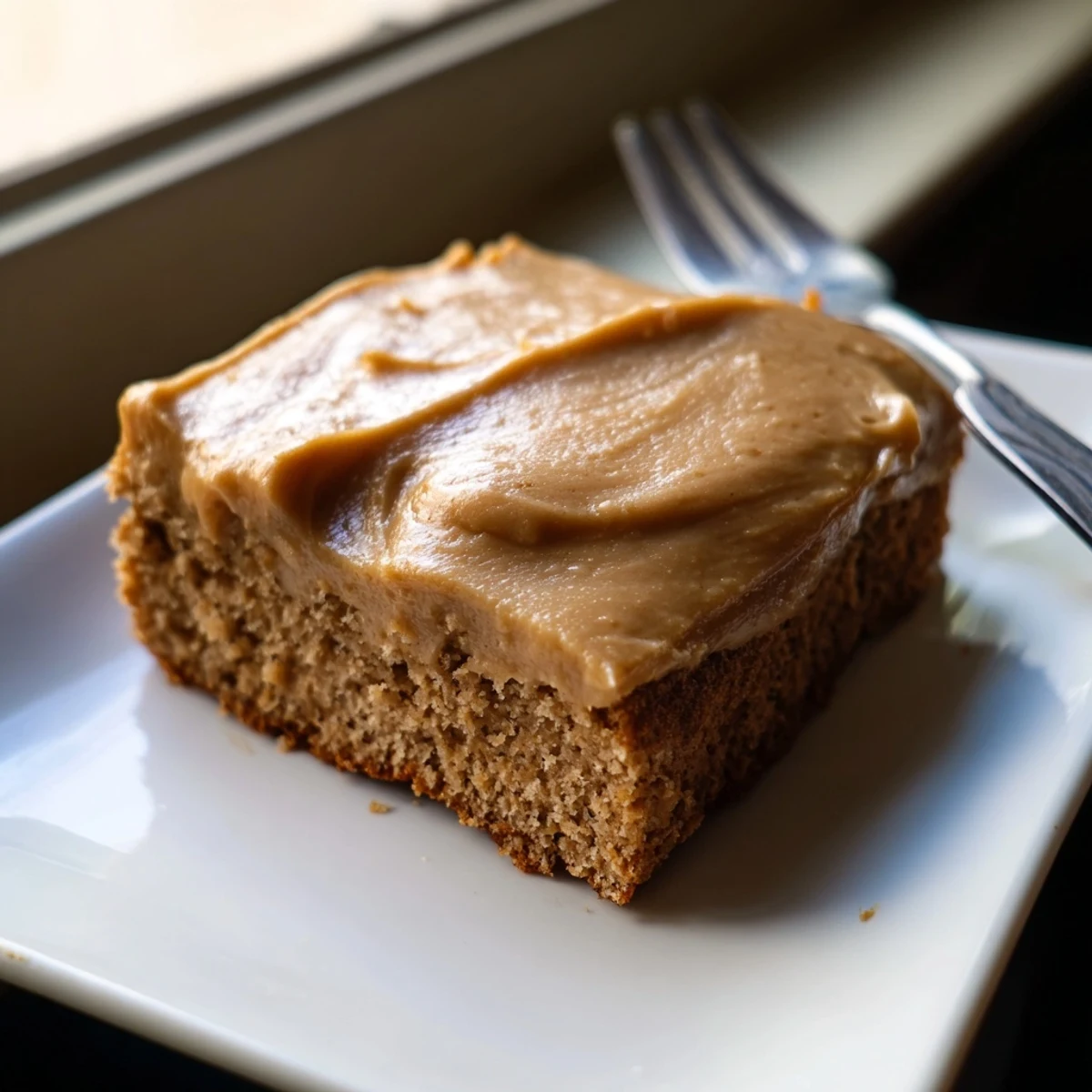 Moist banana bread brownies bars with swirls of nutty brown butter frosting on a cutting board