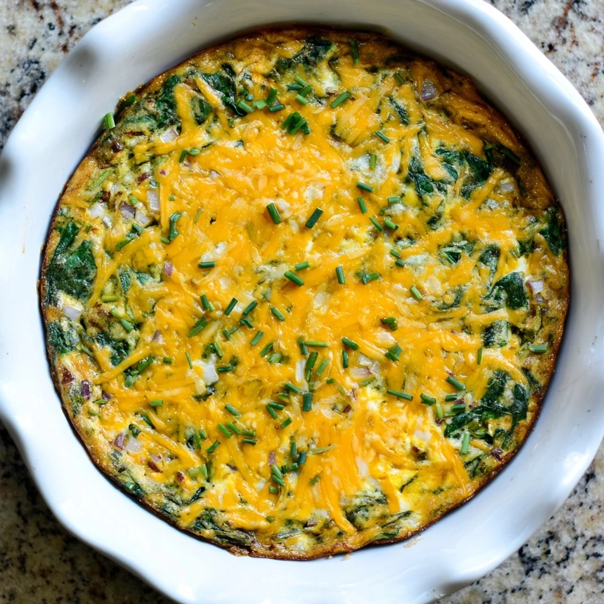 Creamy spinach and cottage cheese quiche sliced into wedges, garnished with green chives on white plate