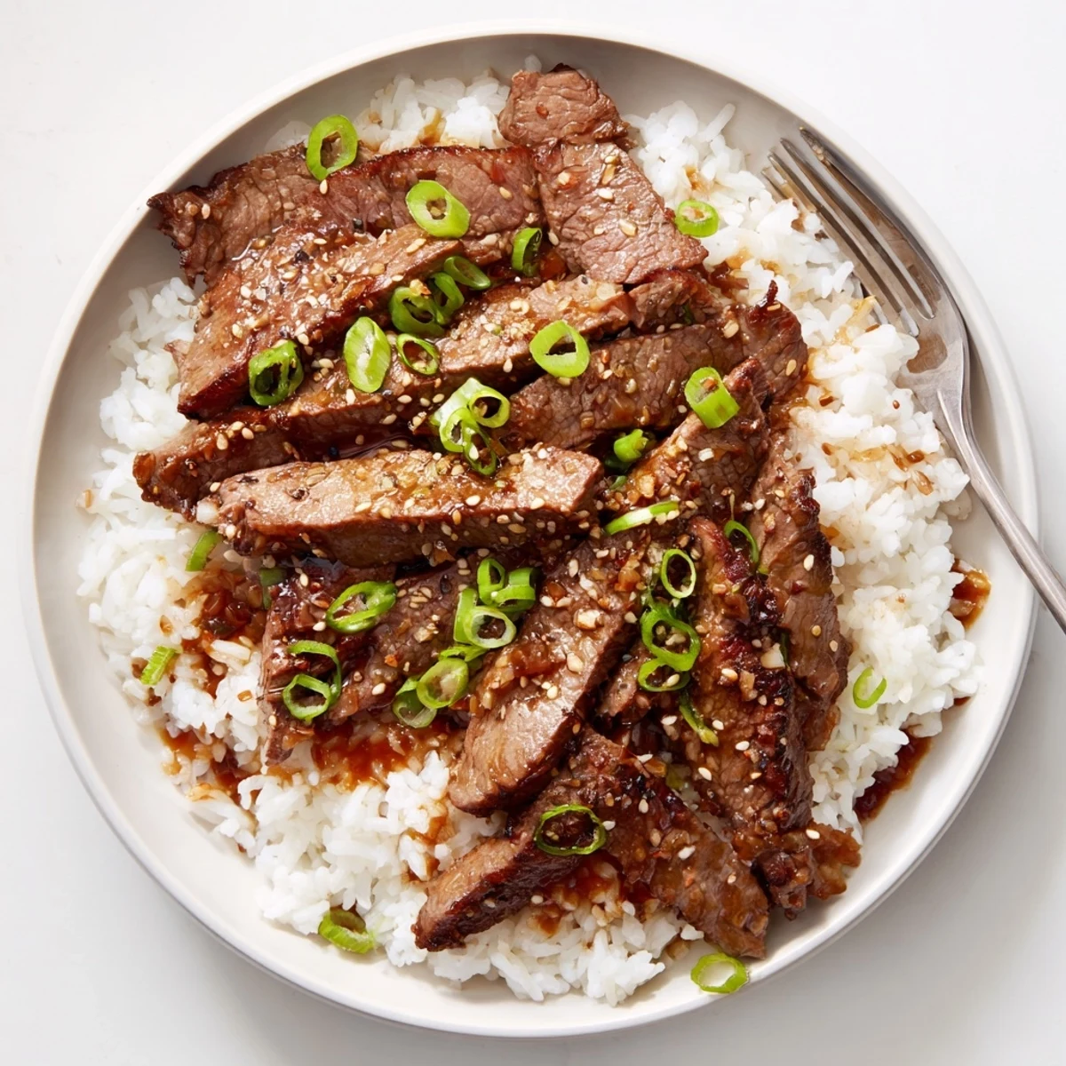 Korean Beef sizzling in a hot skillet, glossy sauce over rice  