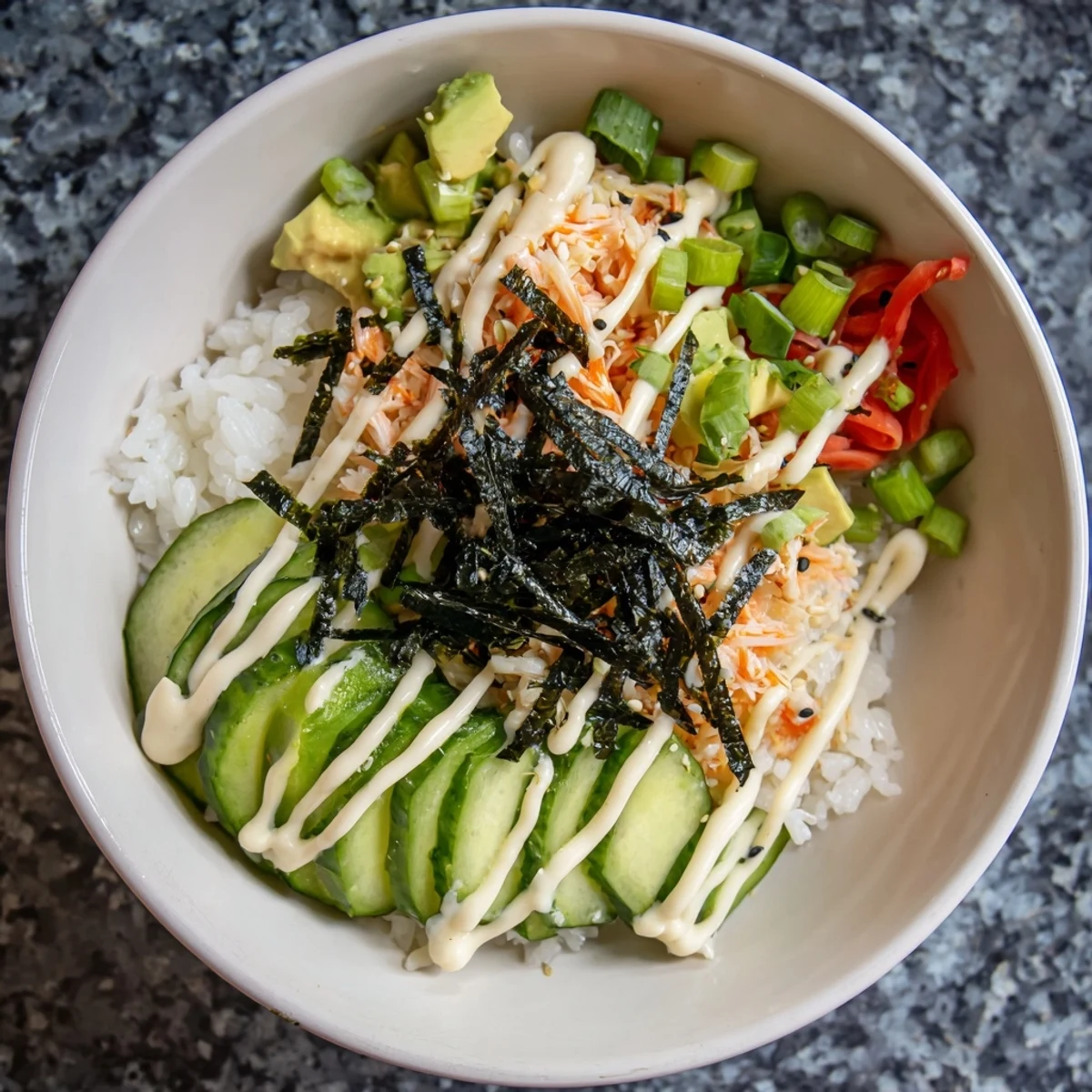 Homemade California roll sushi bowl drizzled with spicy mayo and toasted sesame seeds