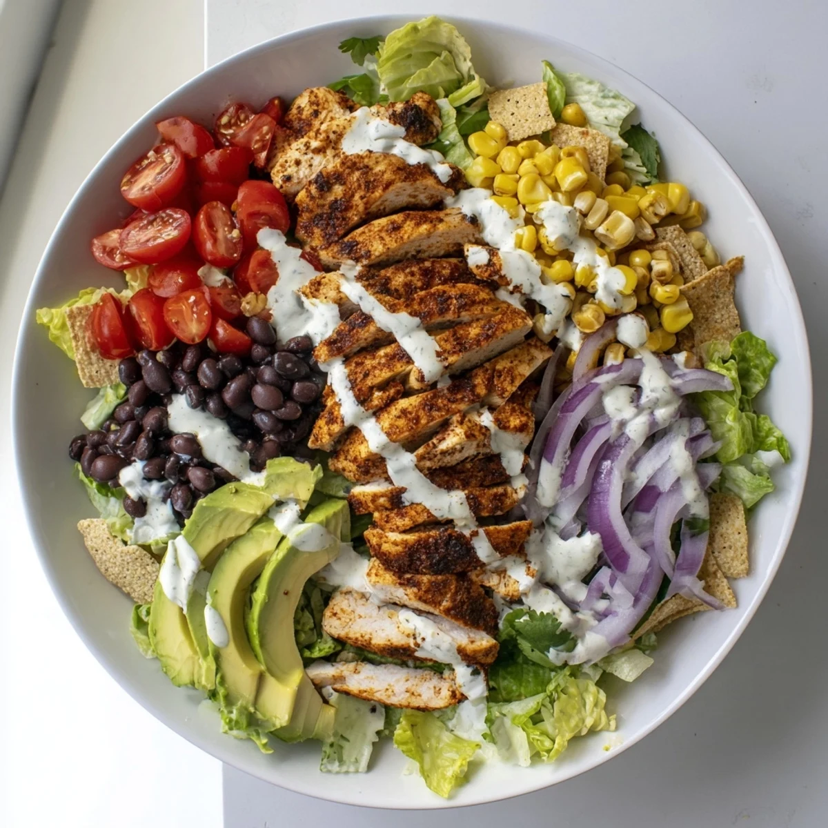 Hearty Southwestern chicken salad packed with seasoned grilled chicken, fresh vegetables, black beans, sweet corn, and sliced avocado topped with tortilla strips