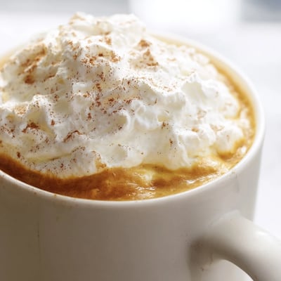 Steaming mug of homemade pumpkin spice latte with frothy milk foam